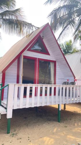 a small house on the beach with a white fence at Eco Wooden Homes in Benaulim