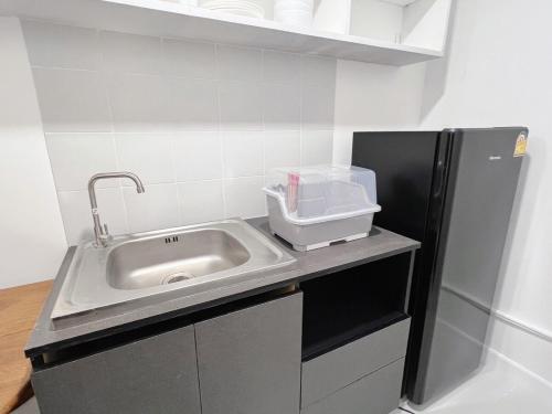 a kitchen with a sink and a refrigerator at Impact - Donmueng Popular C4 in Ban Song Hong