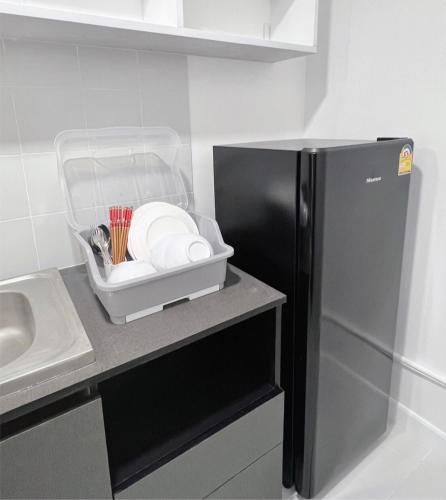 a kitchen with a black refrigerator next to a sink at Impact - Donmueng Popular C4 in Ban Song Hong