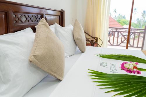 a bed with white sheets and a book with flowers on it at Alfa Boutique Hotel in Kiwengwa