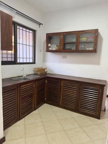 a kitchen with wooden cabinets and a sink at 27 Artful Tegeta holiday home with Inverter in Dar es Salaam