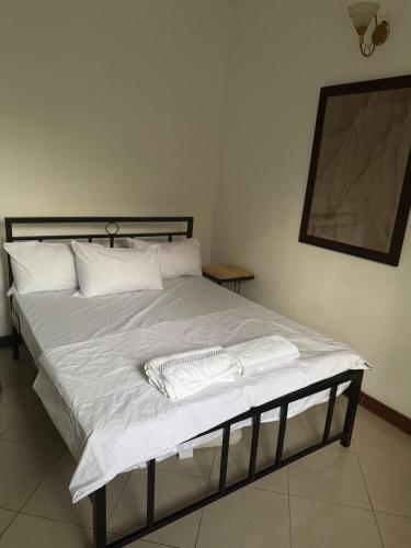 a bed with white sheets and pillows in a bedroom at 27 Artful Tegeta holiday home with Inverter in Dar es Salaam