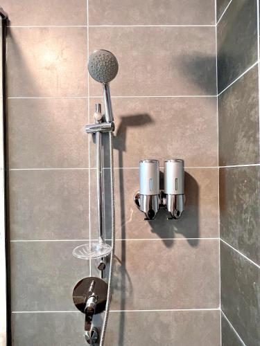 a shower with two cups on a tiled wall at 2-8pax Ipoh Nomado Onsen suites by Sunway Onsen Lost world of Tambun in Ipoh