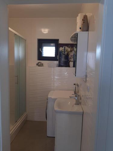 a bathroom with a sink and a tv on the wall at Šućur holiday home in Preko