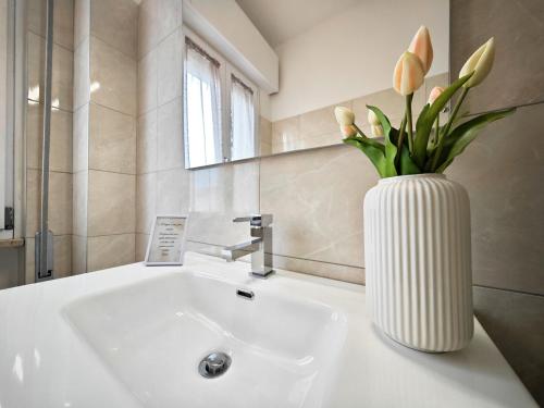 a white vase with flowers on a sink in a bathroom at b&b il Melograno in Berlingo
