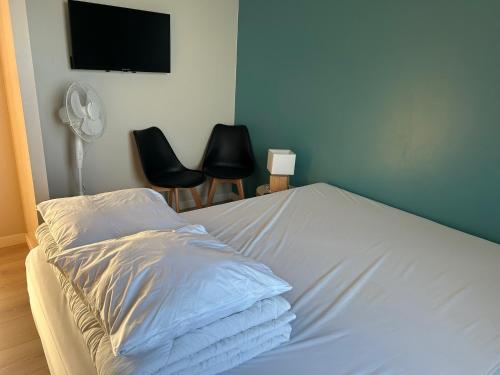 a white bed with two chairs and a flat screen tv at Gîtes Rozanna avec accès détente SPA JACUZZI in Saint-Jean-de-la-Rivière