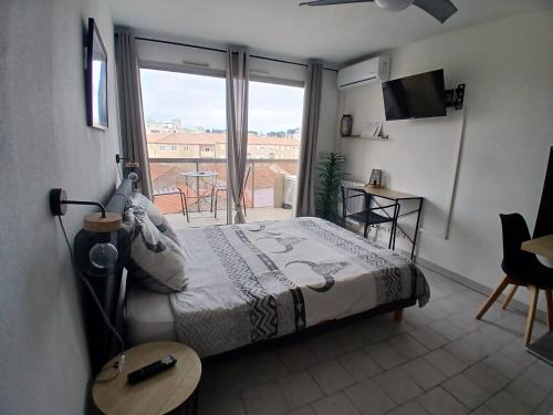 une chambre avec un lit et une vue sur un balcon dans l'établissement Studio clim parking dhuoda, à Nîmes