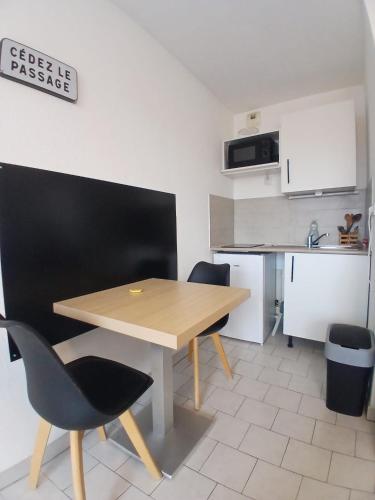 une petite cuisine avec une table et des chaises en bois dans l'établissement Studio clim parking dhuoda, à Nîmes
