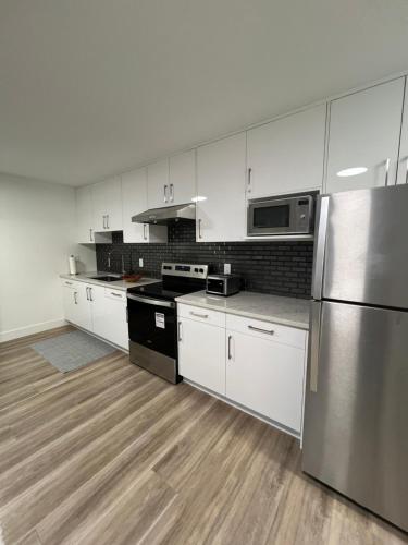 a kitchen with white cabinets and stainless steel appliances at Calm & Cozy Private Suite in Surrey