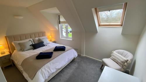 a bedroom with a bed and a window and a chair at Pegasus Lodge in the Cotswolds in South Cerney