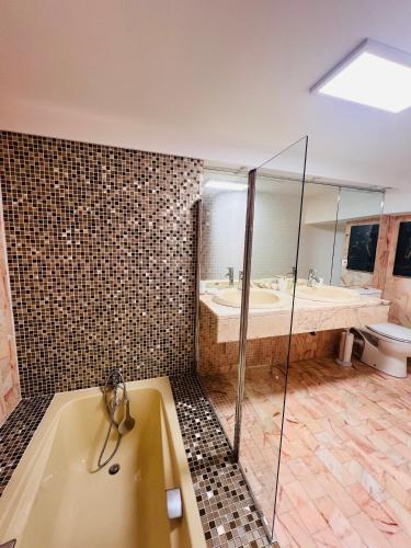 une salle de bain avec une baignoire, une douche et un lavabo dans l'établissement L'Architek, à La Grande Motte