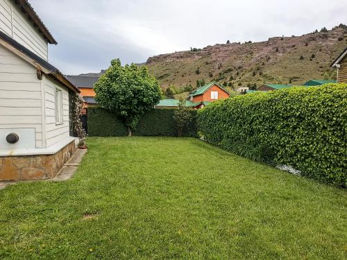 a yard with a hedge and a house at La casa de Gaby in San Martín de los Andes