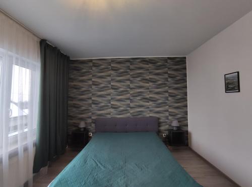 a bedroom with a green bed and a wall at Pokoje Piaskowa 44 in Krynica Morska