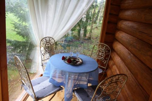 a blue table and chairs on a porch with a window at Bērzlejas in Upesgrīva