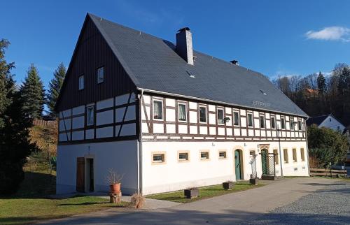 a large white and black building with a black roof at Ferienwohnung im Fachwerkhaus in Sebnitz