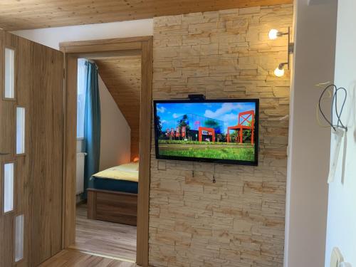 a tv mounted on a brick wall in a room at Květinové apartmány Horní Planá in Horní Planá