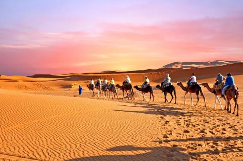 Un grupo de personas montando camellos en el desierto. en Desert Camel Trek, en Merzouga