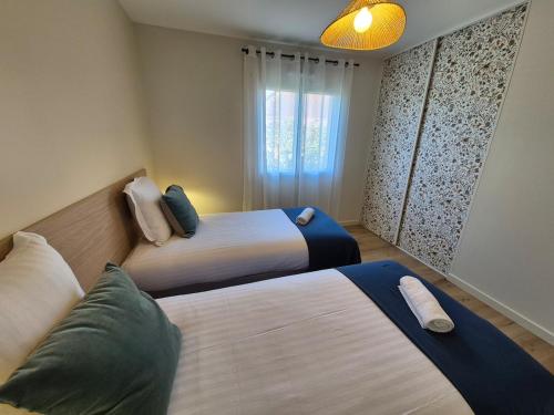 a bedroom with two beds and a window at Le gîte de Midi for 6 pers - Quiet garden in Uzein