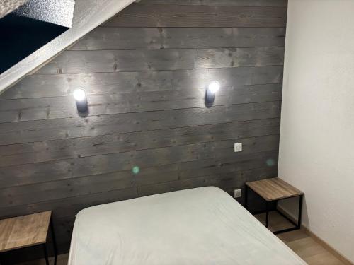 - une chambre avec deux lumières sur un mur en bois dans l'établissement Terrasse 3, à Nancray