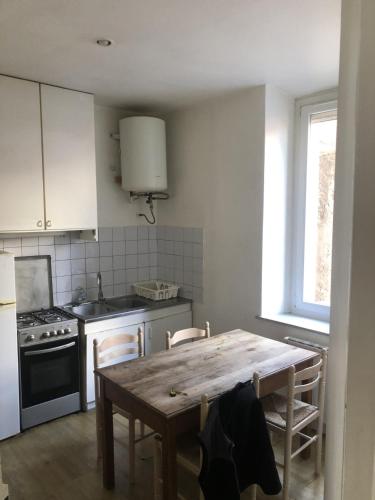 - une cuisine avec une table en bois, des chaises et une cuisinière dans l'établissement Rent4night Grenoble Aigle, à Grenoble