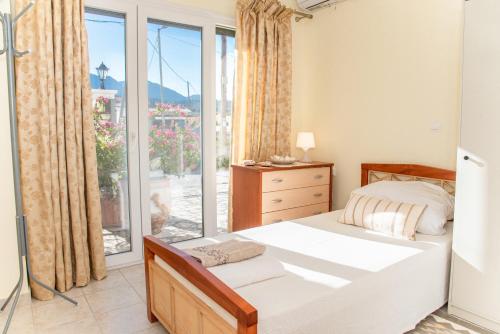 a bedroom with a bed and a large window at Shell & Pebble in Acharavi