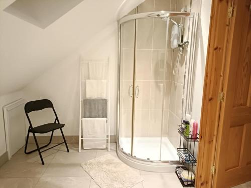 a shower with a black chair in a bathroom at Peartree Cottage in Derryork