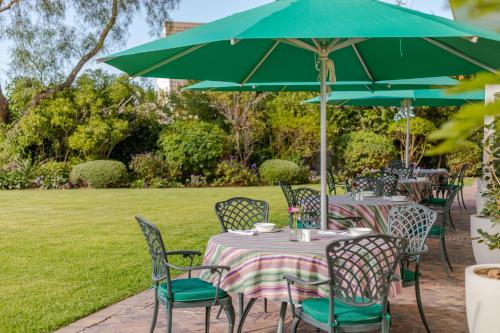 einen Tisch und Stühle unter einem grünen Schirm in der Unterkunft The Helderview Luxury Suites in Somerset West