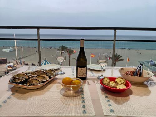 - une table avec une bouteille de vin et une assiette de nourriture dans l'établissement Front de Mer idéal classé 3 étoiles, à Canet