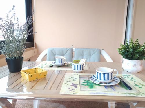 une table en bois avec deux tasses et des assiettes dans l'établissement T2 avec grand balcon filant, Wifi, Clim à 4 min Remparts, à Avignon