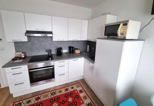 a kitchen with white cabinets and a microwave at RentinAustria in Reisenberg