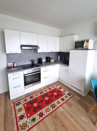 a kitchen with white cabinets and a red rug at RentinAustria in Reisenberg