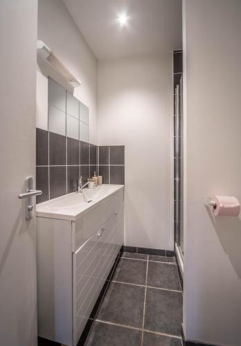 une salle de bain blanche avec un lavabo et une douche dans l'établissement Le refuge citadin, à Tournus
