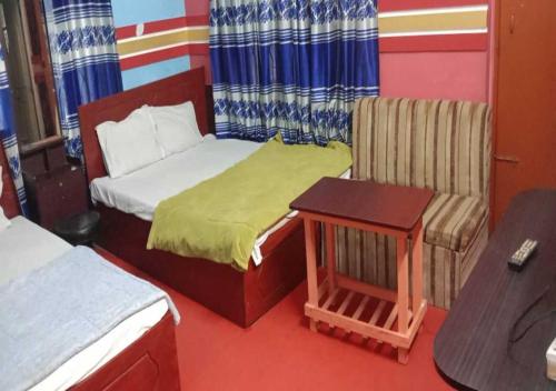 a bedroom with a bed and a chair and a table at The Hotel Golden Star in Khulna