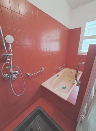 La salle de bains rouge est pourvue d'une baignoire et d'une douche. dans l'établissement Gite Les Quat'vents, à Boulleret