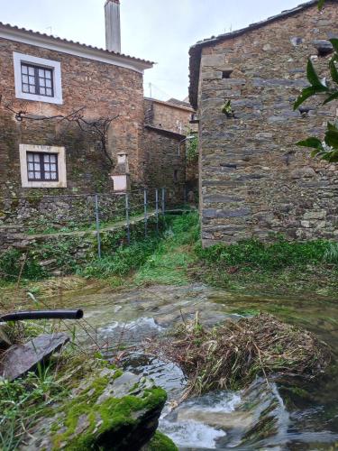 an old stone building with a stream in front of it at Casa Iris Cunqueiros in Sobreira Formosa