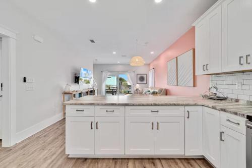 a kitchen with white cabinets and a pink wall at Pink Bungalow w Private Beach! Girls Getaway! in Gulf Shores