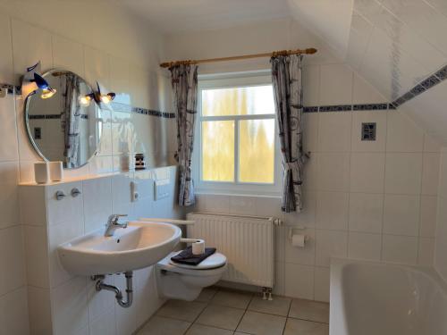 a bathroom with a sink and a toilet and a window at gemütliche Doppelhaushälfte in Burhave in Burhave