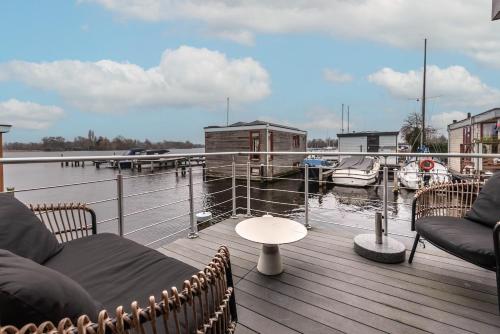 a deck with chairs and a table and a marina at Spacious 120m2 Water Villa With Sauna Near Amsterdam in Aalsmeer