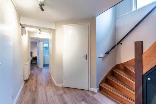 a hallway with a white door and wooden stairs at Spacious 120m2 Water Villa With Sauna Near Amsterdam in Aalsmeer