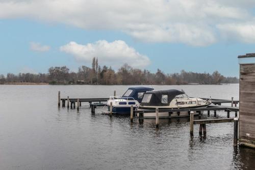 two boats are docked at a dock on a lake at Spacious 120m2 Water Villa With Sauna Near Amsterdam in Aalsmeer