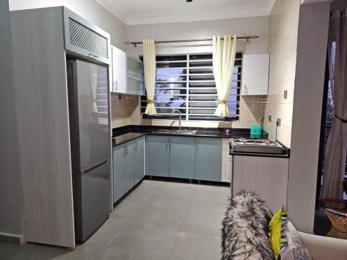 a kitchen with a stainless steel refrigerator and a window at Ripple House in Namulanda