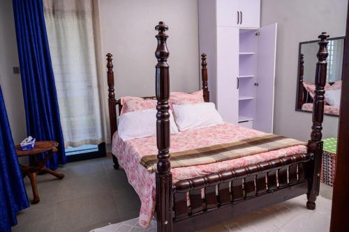 a bedroom with a bed with a wooden frame at Ripple House in Namulanda