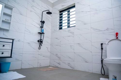 a bathroom with a shower with white marble walls at Ripple House in Namulanda