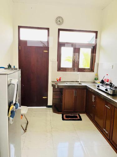 a kitchen with wooden cabinets and a window and a door at Rainforest Mount Villa in Nelluwa