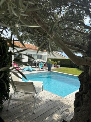 - une piscine avec une chaise à côté d'une maison dans l'établissement Villa Horizon Ré, à LʼHoumeau