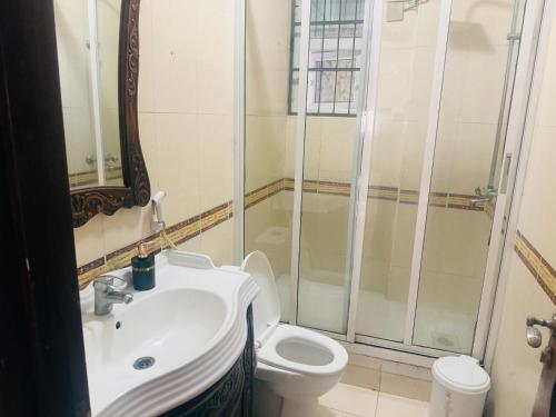 a bathroom with a toilet and a sink and a shower at Two- Bedroom Masaki Sea View Retreat in Dar es Salaam