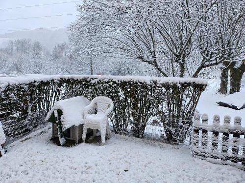 deux chaises couvertes de neige à côté d'une clôture dans l'établissement Kiki, à La Bourboule