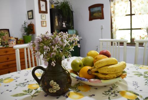 a table with a bowl of fruit and a vase of flowers at Pansion Savinac in Takovo