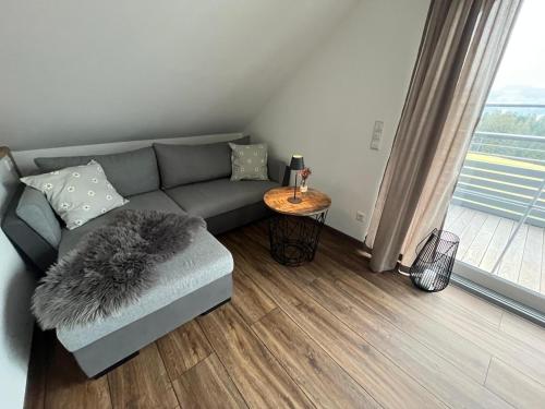 a living room with a gray couch and a table at Ferienwohnung Schneider in Weiler-Simmerberg