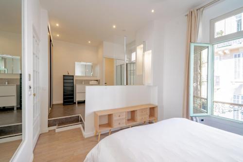 une chambre avec un lit blanc et une table dans l'établissement Bel appartement avec balcon centre ville, à Cannes
